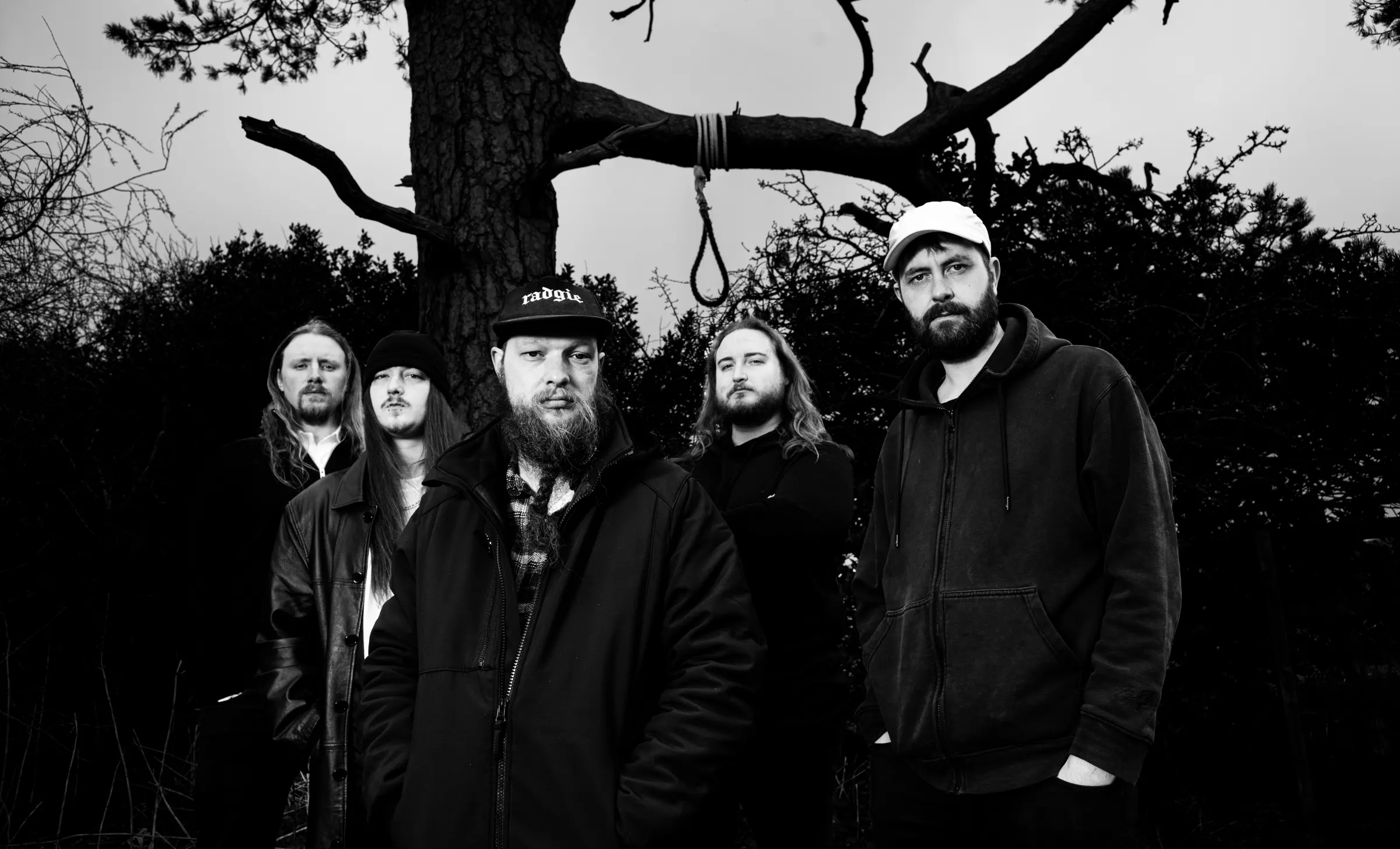 The members of Fateweaver standing beneath a bare tree, in black and white